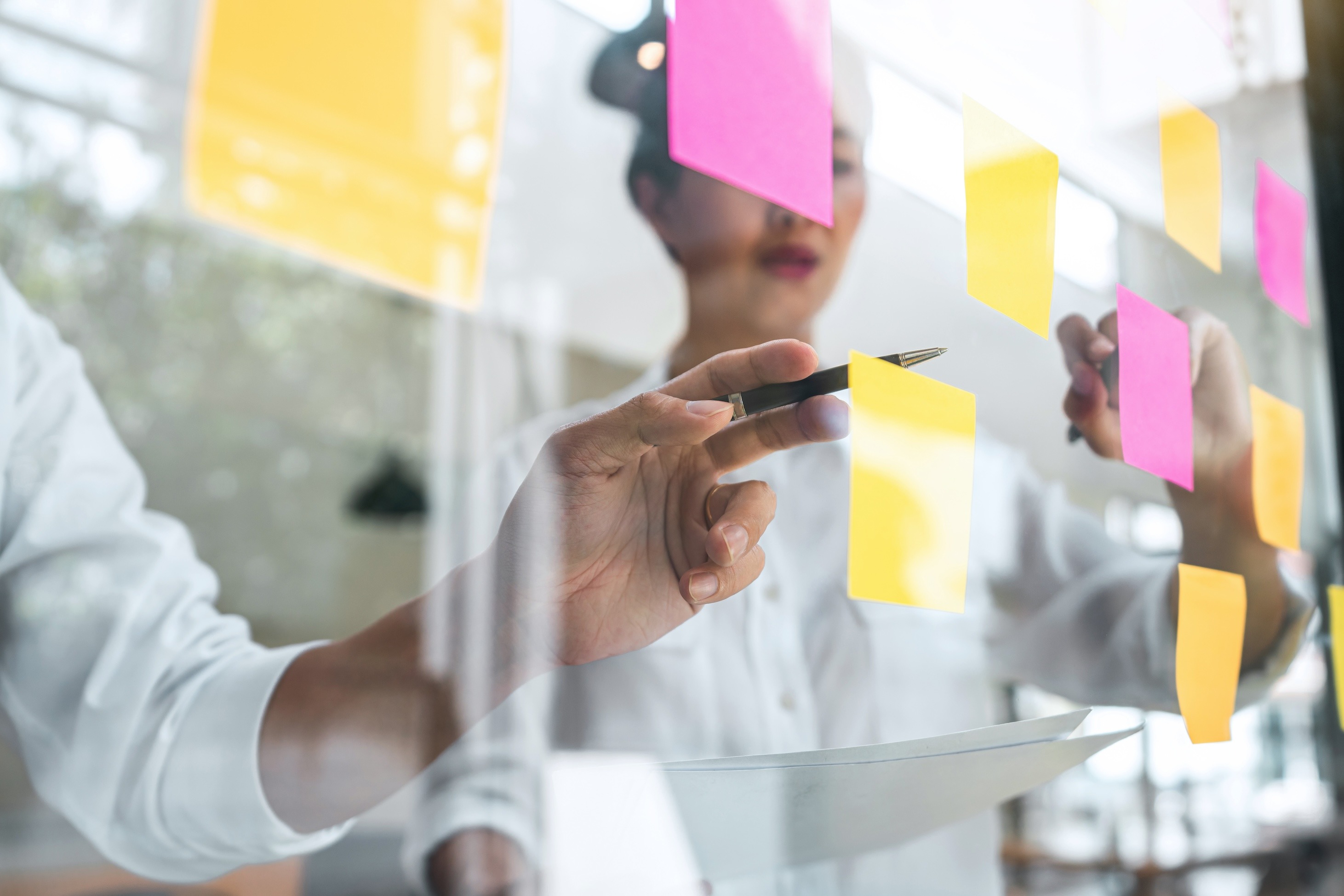 Person pointing at sticky notes on glass window