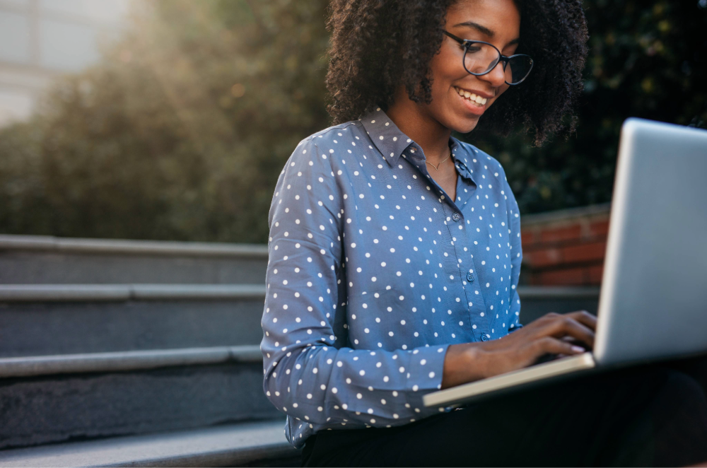 Woman sitting on a park bench using laptop