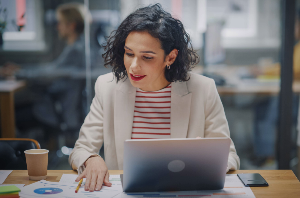 Advertiser sitting at desk on laptop and reading notes