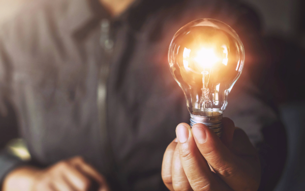 Person holding a lit light bulb