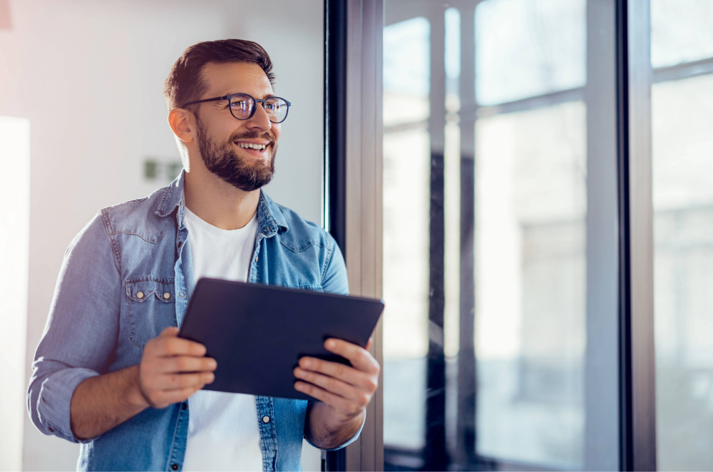 Man in office setting holding tablet and smiling